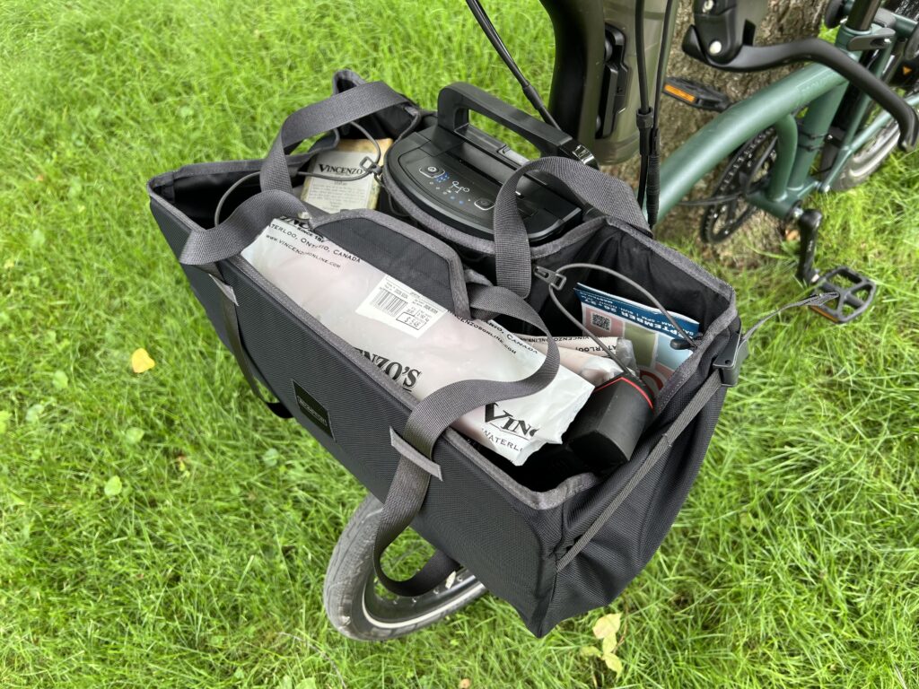 A 3/4 overhead view of a bag on the front of a bike. Various groceies can be seen filling the bag.